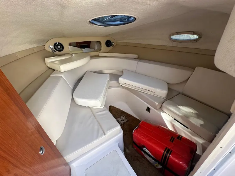 Slide: The Image of 2006 Regal 2450 Cuddy cabin interior with white seating and portholes. - 24
