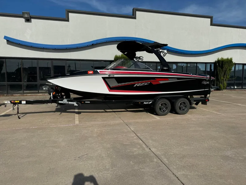 Slide: The Image of 2016 Tigé RZ2 boat on trailer, parked outside a building. - 1