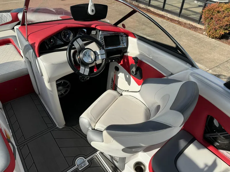 Slide: The Image of Interior of a 2016 Tigé RZ2 boat with red and white seating, modern dashboard. - 6