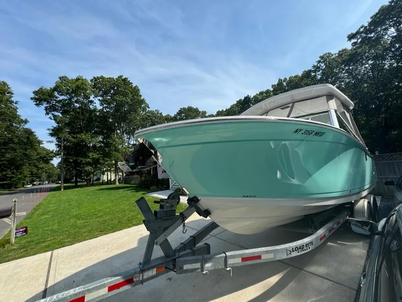 Slide: The Image of 2020 Blackfin 272 DC boat on trailer, parked in a driveway, surrounded by trees. - 3