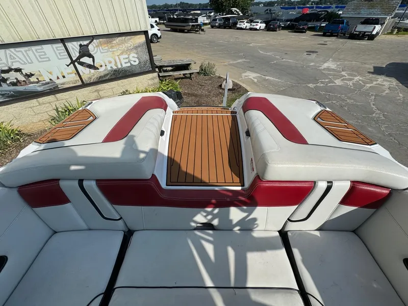Slide: The Image of 2014 Nautique G23 boat interior with red and white seating, wooden accents, and outdoor setting. - 10