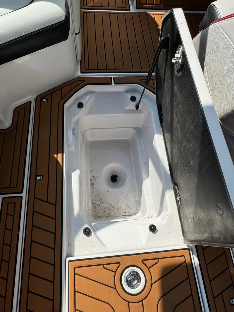 Slide: The Image of 2014 Nautique G23 boat storage compartment with open lid and teak flooring. - 14
