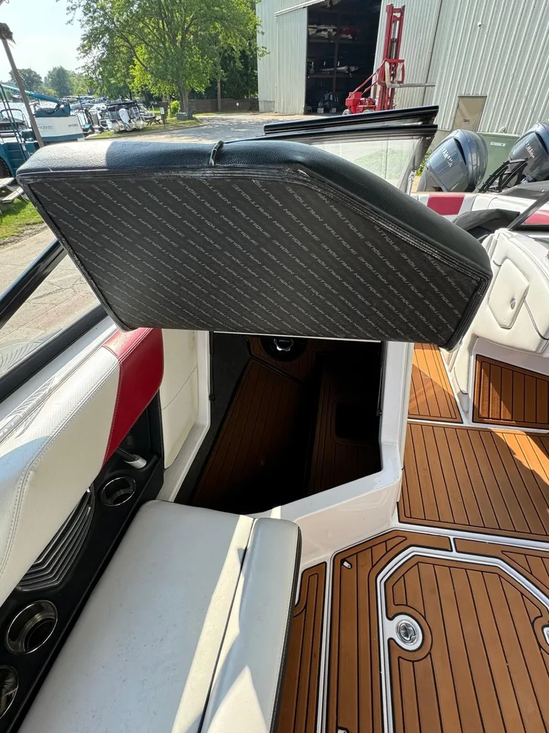 Slide: The Image of 2014 Nautique G23 interior with open storage compartment and teak flooring. - 16