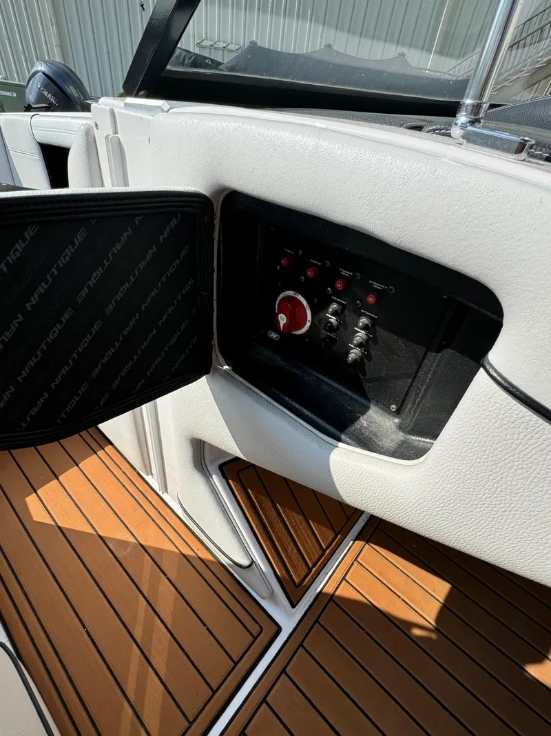 Slide: The Image of 2014 Nautique G23 boat control panel with switches and teak flooring. - 22