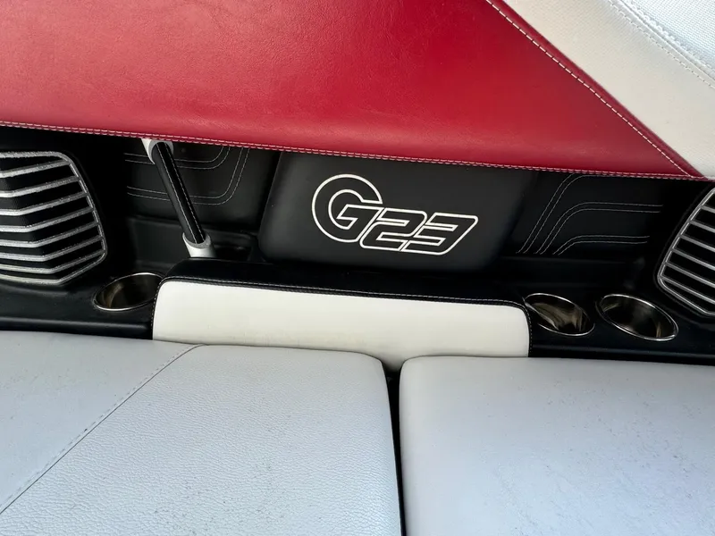 Slide: The Image of 2014 Nautique G23 boat interior with red and white upholstery, cup holders, and logo. - 27