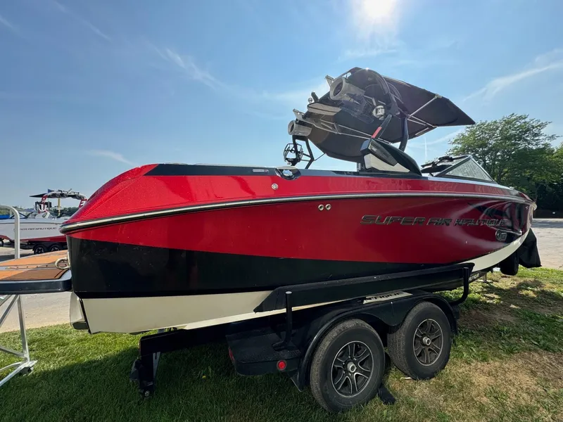 Slide: The Image of 2014 Nautique G23 boat in red and black on a trailer under clear sky. - 3