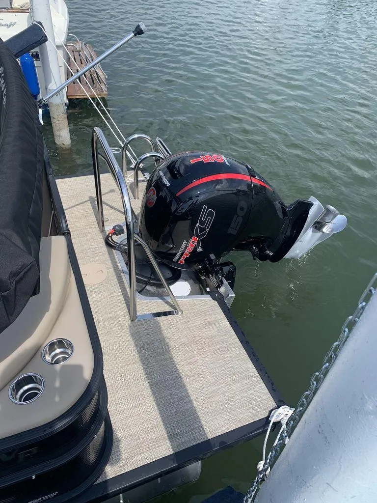 Slide: The Image of 2022 Manitou 23 Aurora LE VP boat with powerful outboard motor on water. - 2