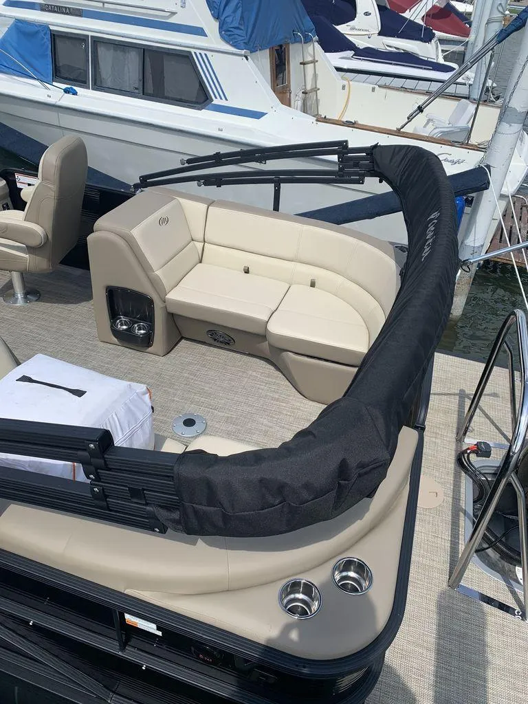 Slide: The Image of 2022 Manitou 23 Aurora LE VP pontoon boat with beige seating and cup holders. - 3