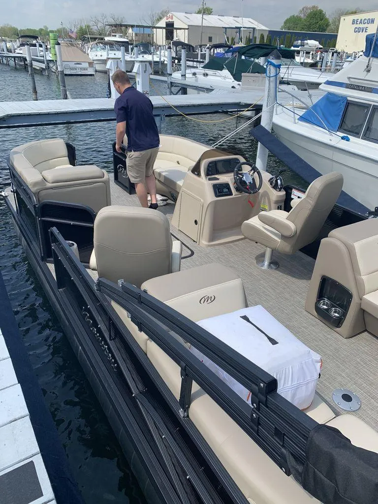 Slide: The Image of 2022 Manitou 23 Aurora LE VP pontoon boat docked at marina with beige seating. - 4