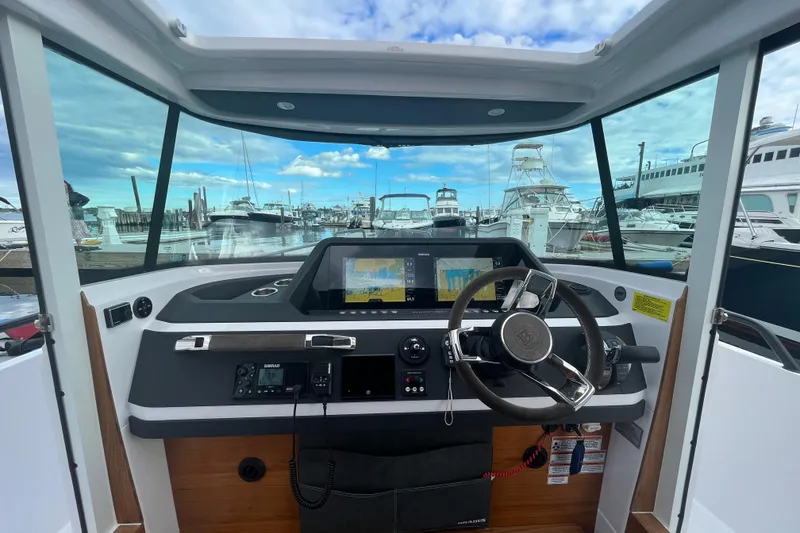 Slide: The Image of 2022 Axopar 28 CABIN helm with modern navigation displays and marina view. - 18