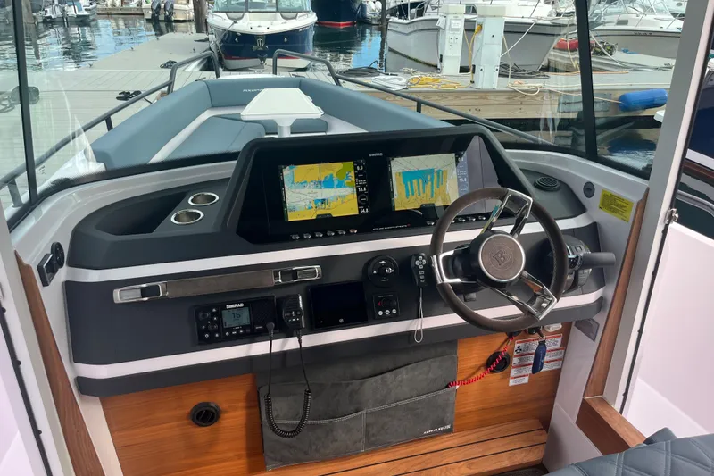 Slide: The Image of 2022 Axopar 28 CABIN boat dashboard with navigation screens and steering wheel. - 19