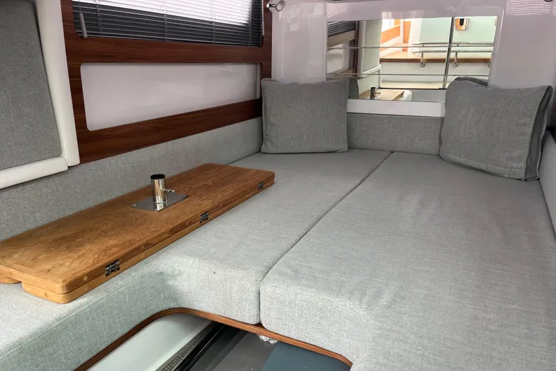 Slide: The Image of Cozy interior of 2022 Axopar 28 CABIN with gray cushions and wooden table. - 28
