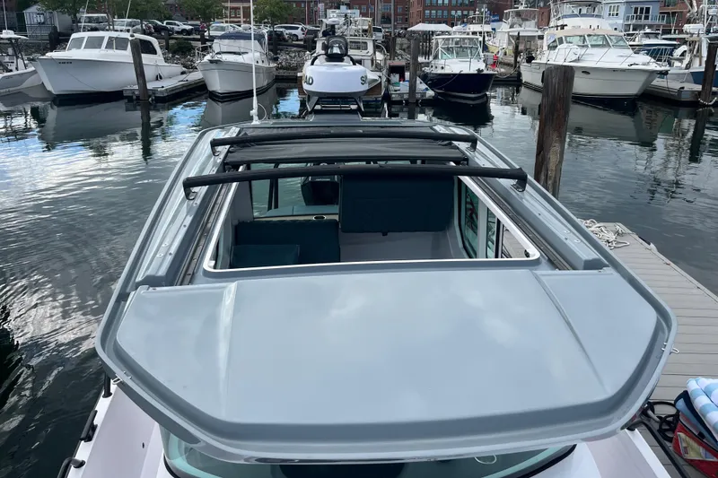 Slide: The Image of 2022 Axopar 28 CABIN boat docked at a marina, surrounded by other vessels. - 4