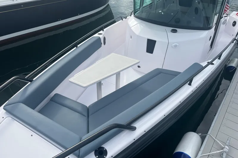 Slide: The Image of 2022 Axopar 28 CABIN boat with sleek seating and table, docked at marina. - 5