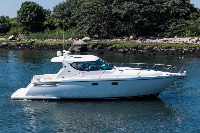 Slide: The Image of 2007 Tiara Yachts 4300 Sovran cruising on calm water near a rocky shoreline. - 12
