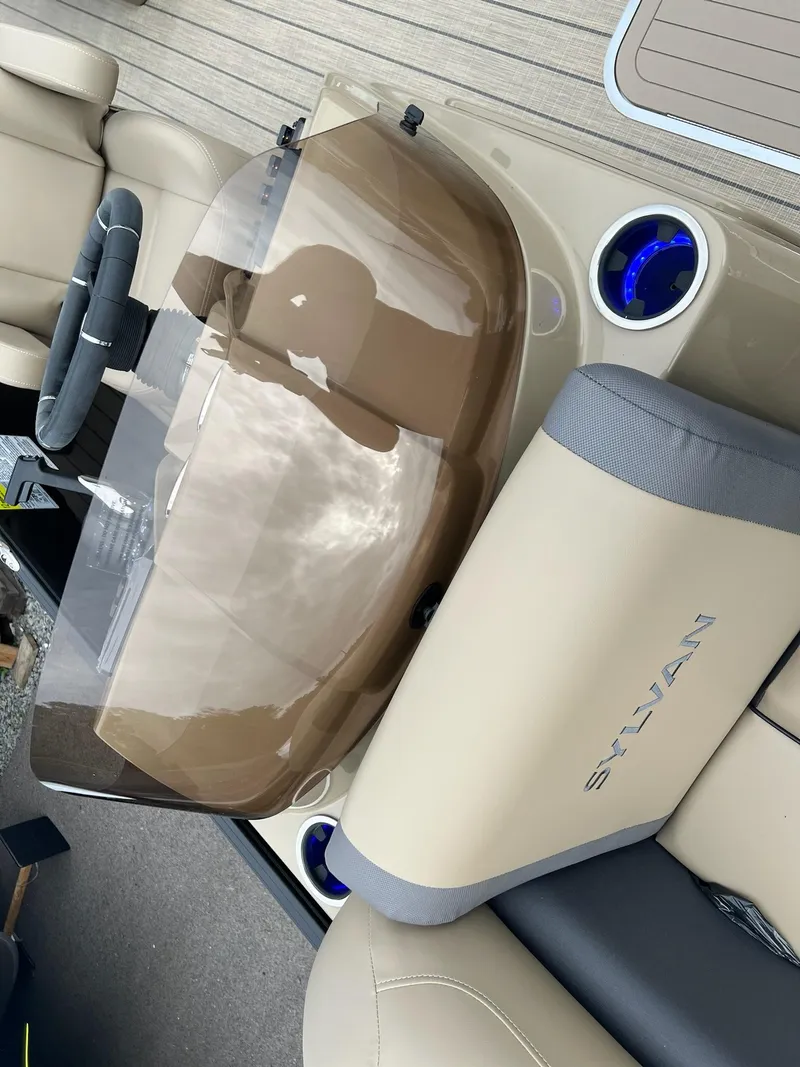 Slide: The Image of 2025 Sylvan X3 CLZ DH Mirage Tritoon interior with beige seating and steering console. - 10