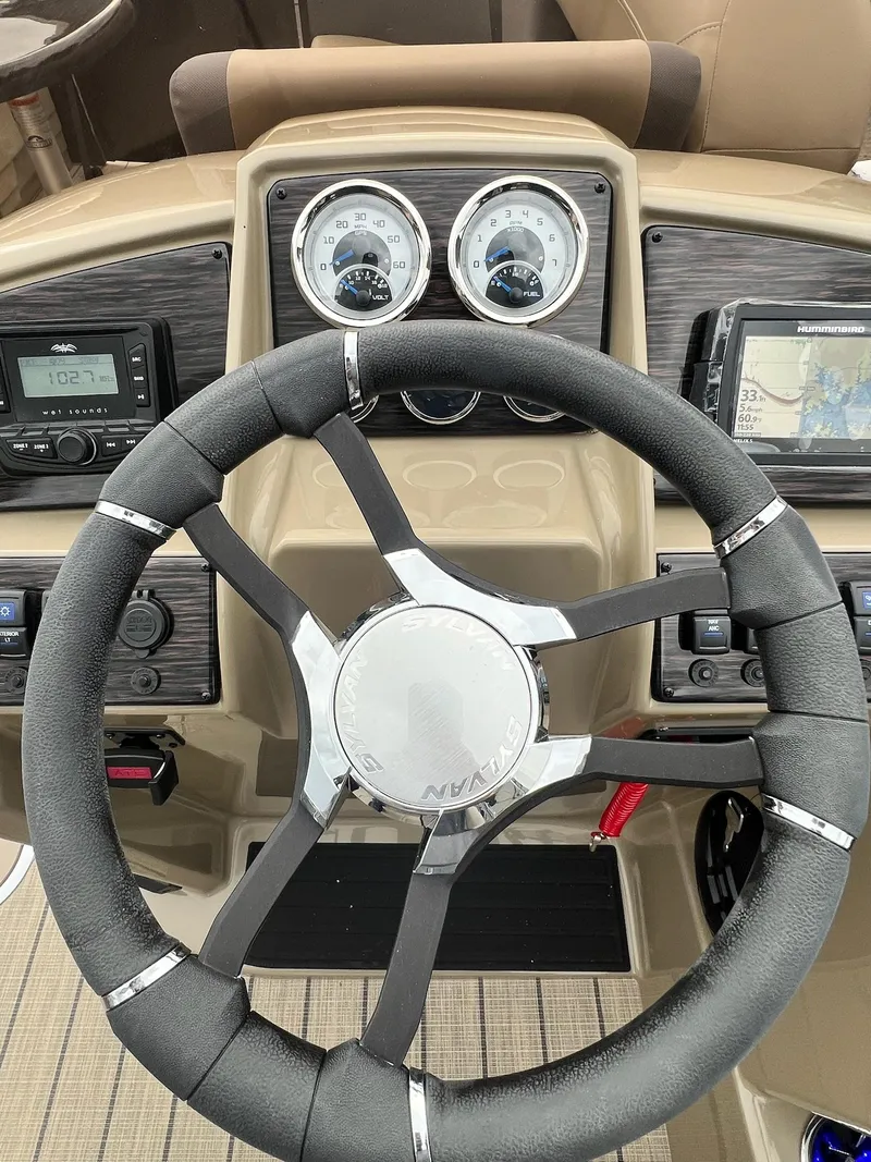 Slide: The Image of 2025 Sylvan X3 CLZ DH Mirage Tritoon dashboard with steering wheel and gauges. - 24
