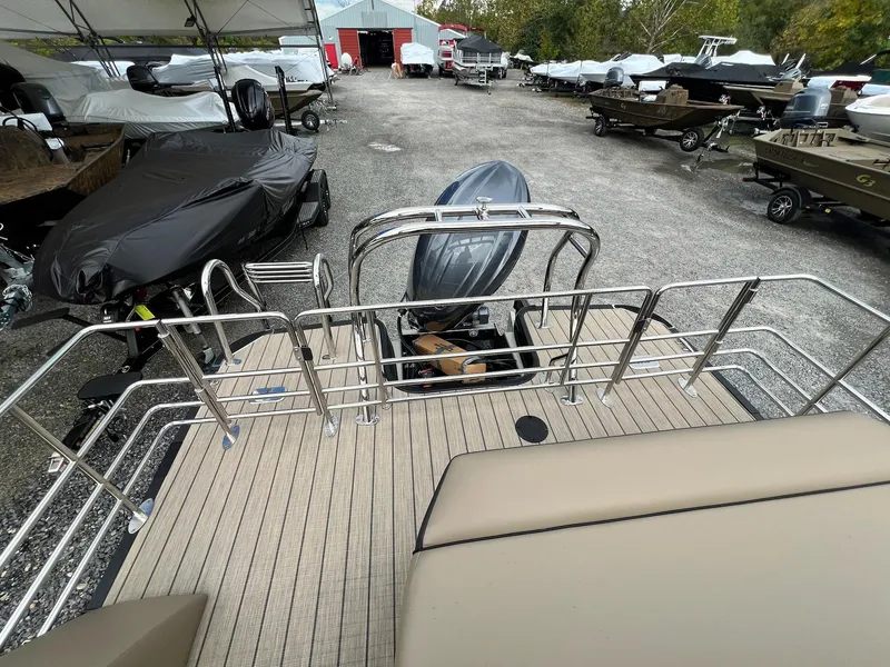 Slide: The Image of 2025 Sylvan X3 CLZ DH Mirage Tritoon in a boatyard, surrounded by covered boats. - 25