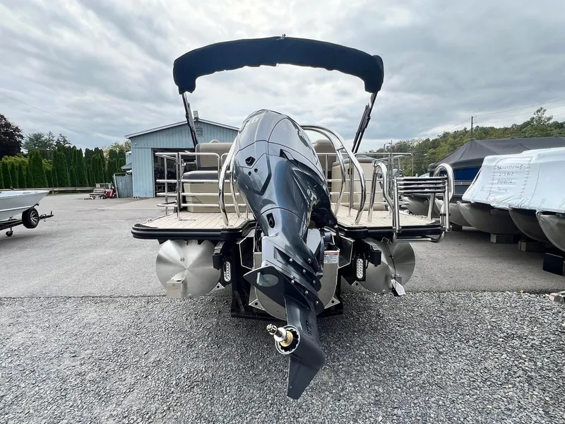 Slide: The Image of 2025 Sylvan X3 CLZ DH Mirage Tritoon boat with outboard motor, parked outdoors. - 32