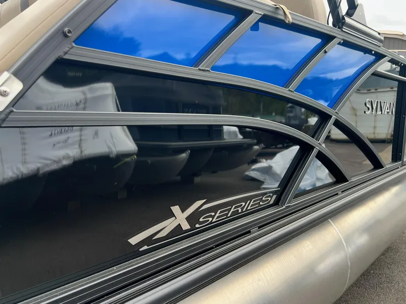 Slide: The Image of 2025 Sylvan X3 CLZ DH Mirage Tritoon boat with sleek design and blue accents. - 36