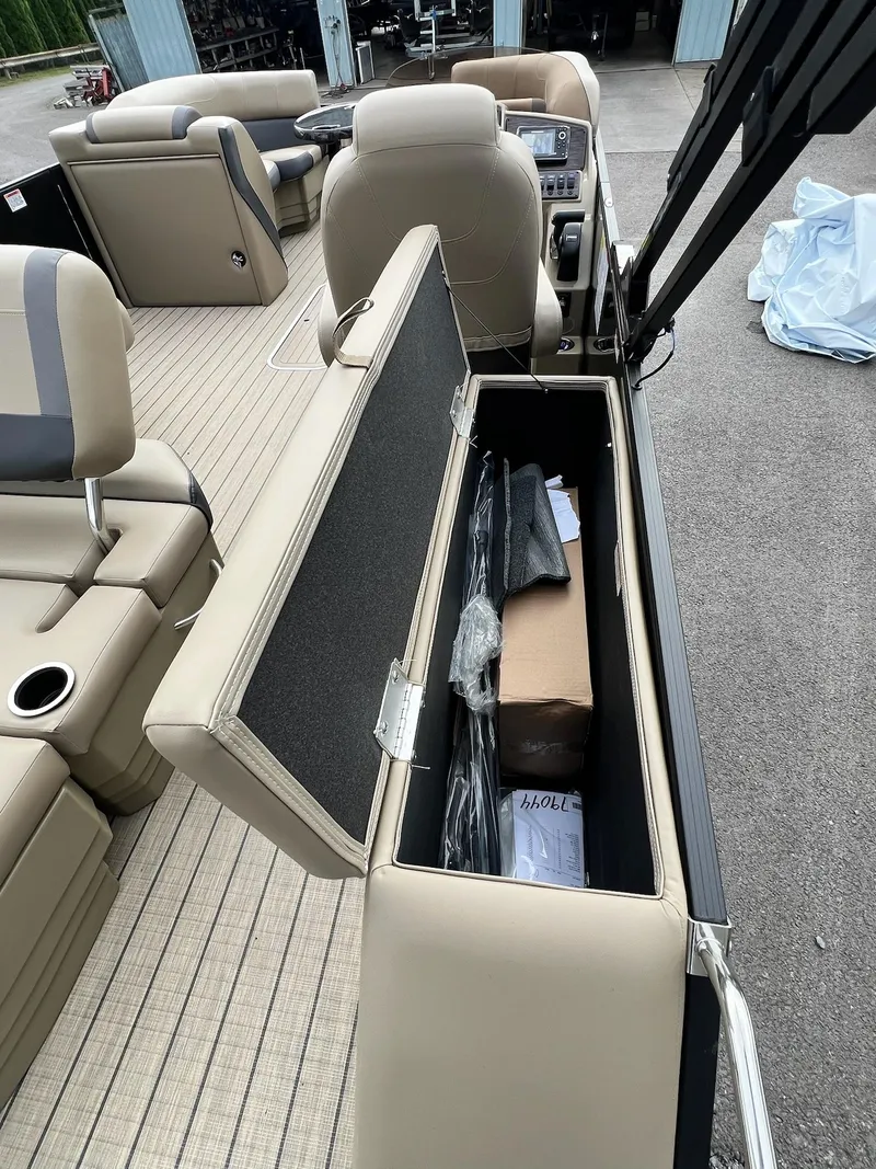 Slide: The Image of 2025 Sylvan X3 CLZ DH Mirage Tritoon interior storage compartment open, showcasing seating and console. - 41