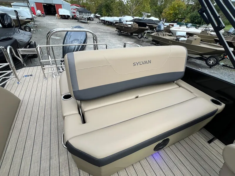 Slide: The Image of 2025 Sylvan X3 CLZ DH Mirage Tritoon boat interior with beige seating and cup holders. - 6