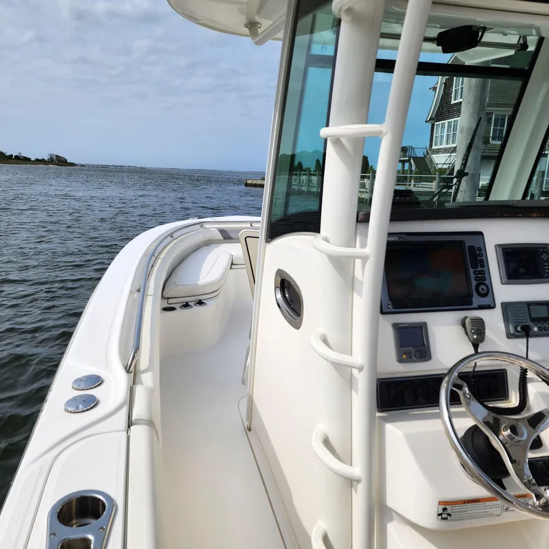 Slide: The Image of 2010 Boston Whaler 320 Outrage boat interior with steering wheel and controls, docked by the water. - 5