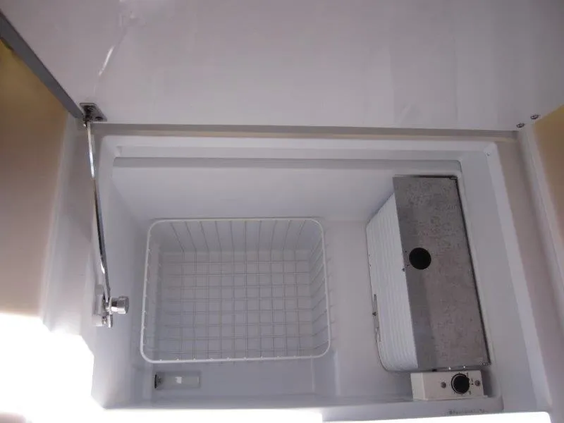 Slide: The Image of 2025 Jeanneau 380 yacht interior fridge with wire basket and cooling unit. - 10