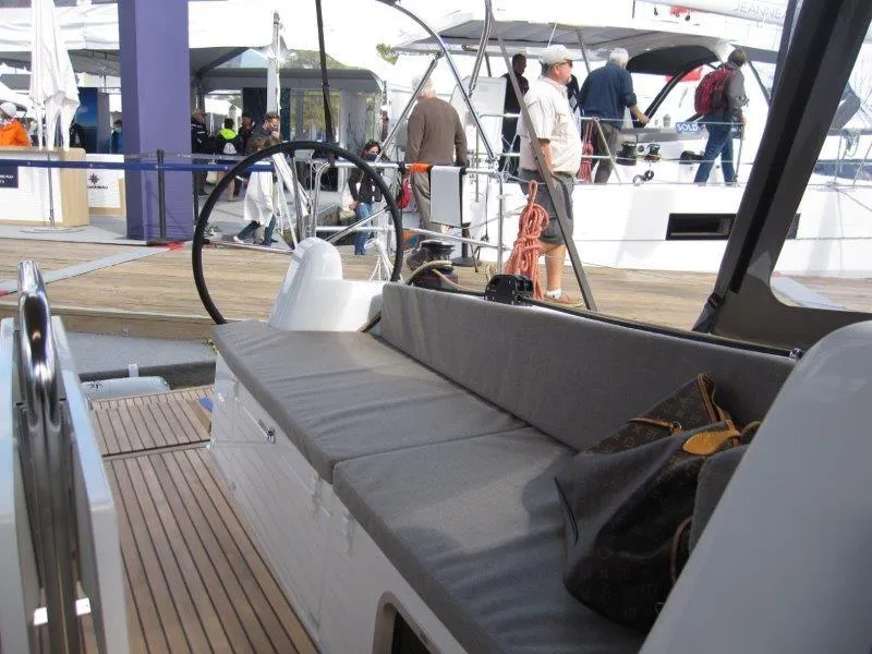 Slide: The Image of 2025 Jeanneau 380 sailboat interior with seating and steering wheel at a boat show. - 18
