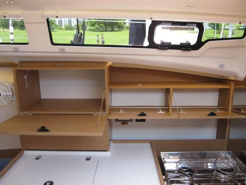 Slide: The Image of Interior of 2025 Jeanneau Sun Odyssey 350 yacht with open wooden cabinets and stove. - 44