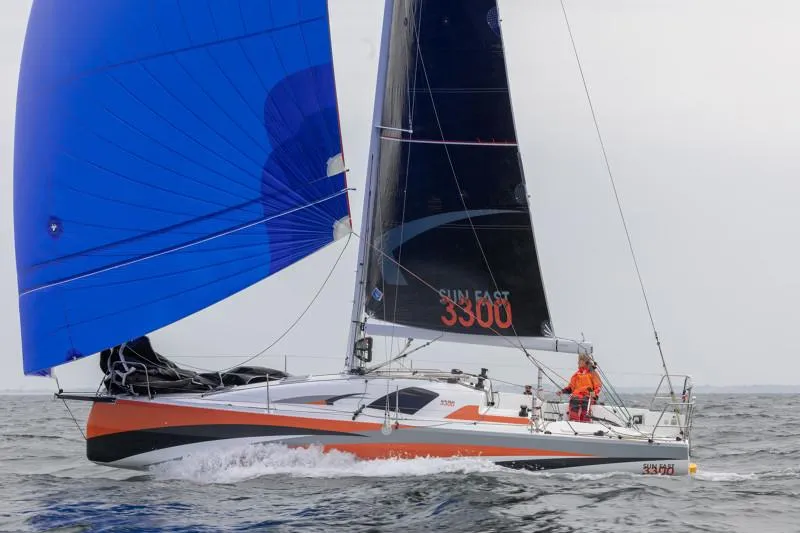 Slide: The Image of 2025 Jeanneau Sun Fast 3300 sailing with blue and black sails on open water. - 34