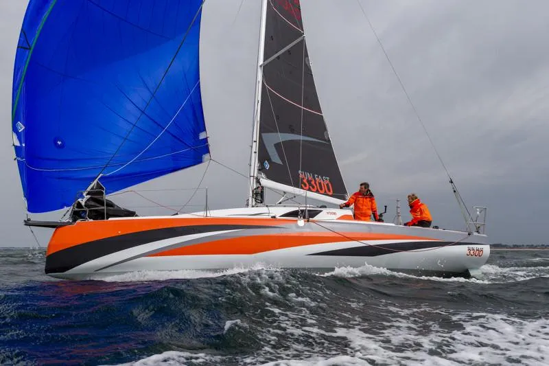 Slide: The Image of 2025 Jeanneau Sun Fast 3300 sailing with vibrant blue and orange sails on open water. - 43