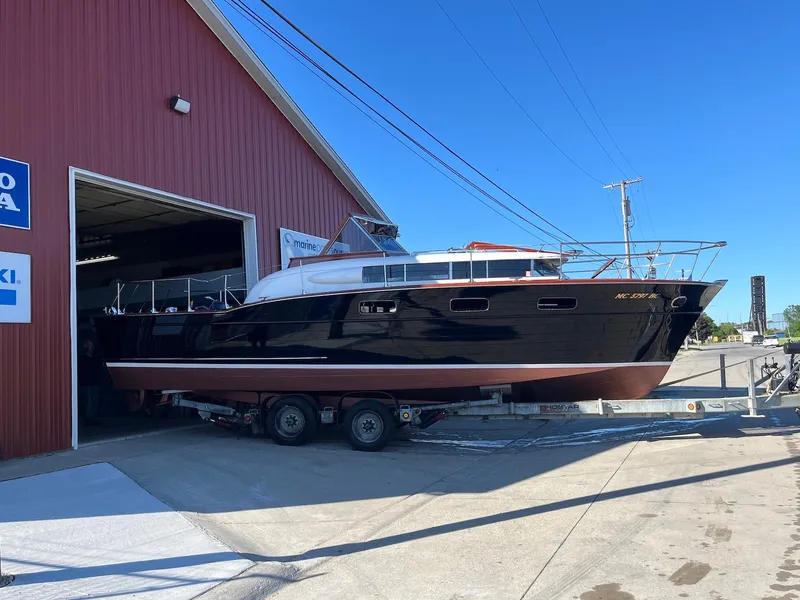 Slide: The Image of 1957 Chris-Craft 33 Futura boat on trailer outside a red building under clear blue sky. - 19