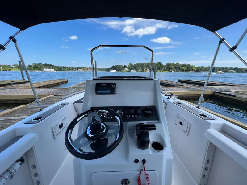 Slide: The Image of 2024 Starcraft SVX 211 OB CC boat cockpit with steering wheel, docked on a sunny day. - 10