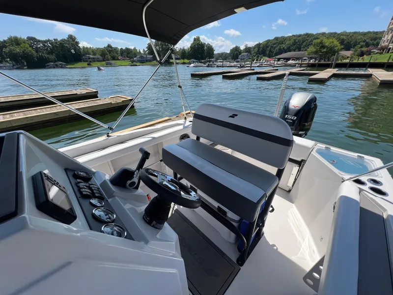 Slide: The Image of 2024 Starcraft SVX 211 OB CC boat interior with steering console, seating, and lake view. - 6
