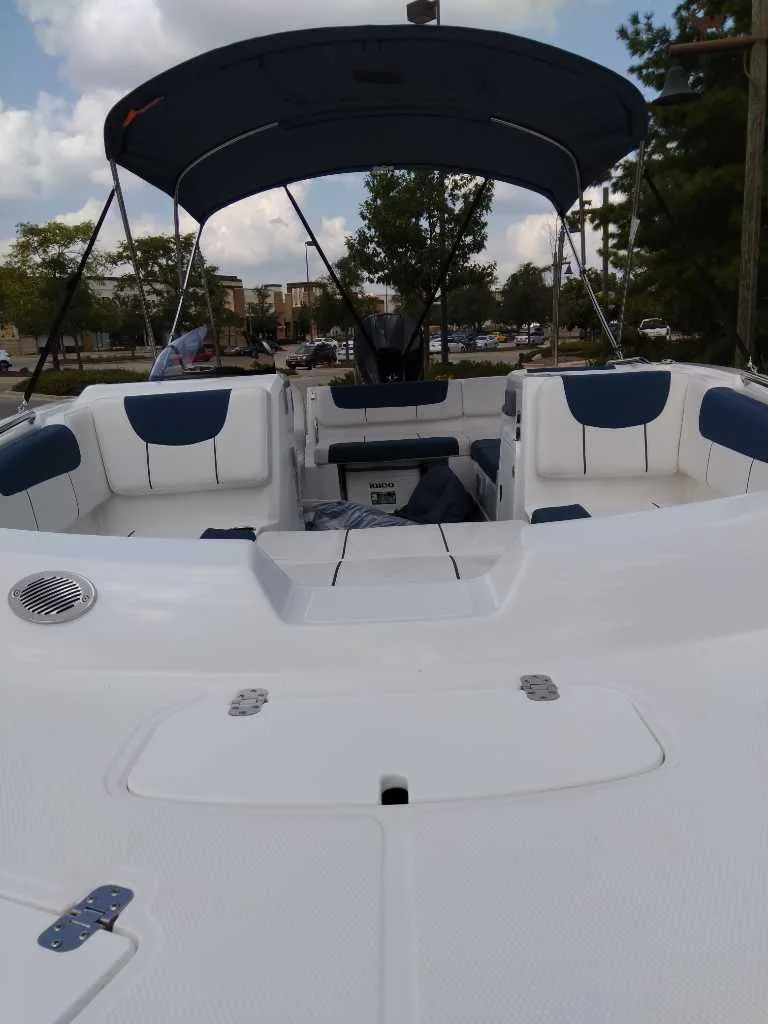 Slide: The Image of 2024 Tahoe 2150 boat with spacious seating and canopy, docked outdoors. - 2
