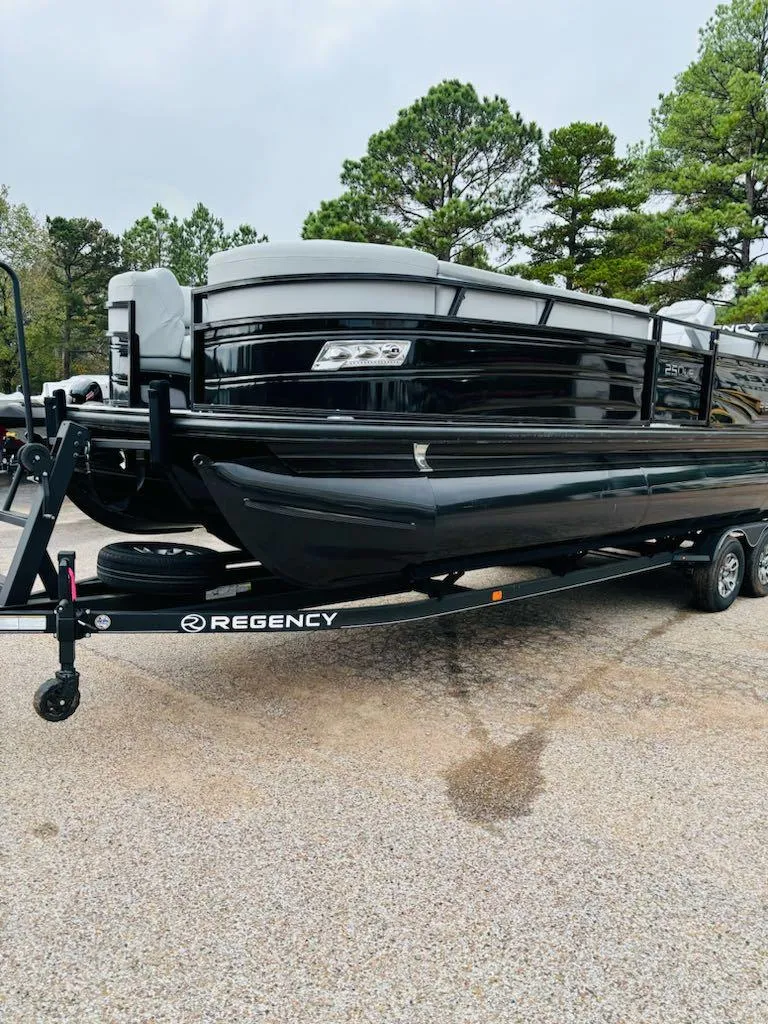 Slide: The Image of 2024 Regency 250 LE3 pontoon boat on trailer, parked outdoors. - 3