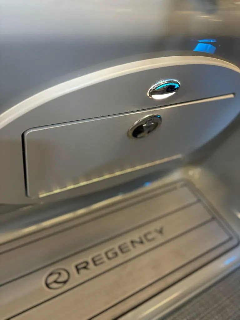 Slide: The Image of 2024 Regency 250 LE3 boat interior with storage compartment and logo. - 8