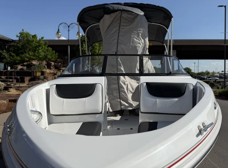 Slide: The Image of 2024 Tahoe 200 S boat with covered seating, parked outdoors under clear sky. - 11
