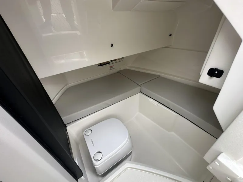 Slide: The Image of 2024 Sea Ray SDX 250 Outboard interior cabin with seating and portable toilet. - 11