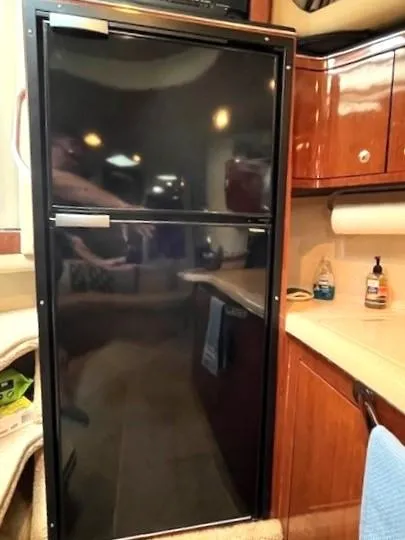 Slide: The Image of 2003 Sea Ray 38 Sundancer kitchen with black fridge and wooden cabinetry. - 9