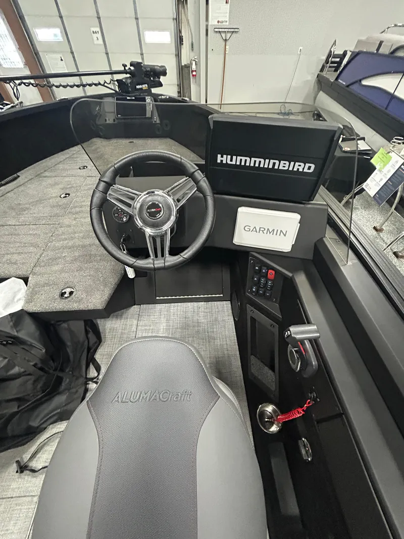 Slide: The Image of 2025 Alumacraft Competitor 175X CS boat interior with open storage compartment and seat. - 6
