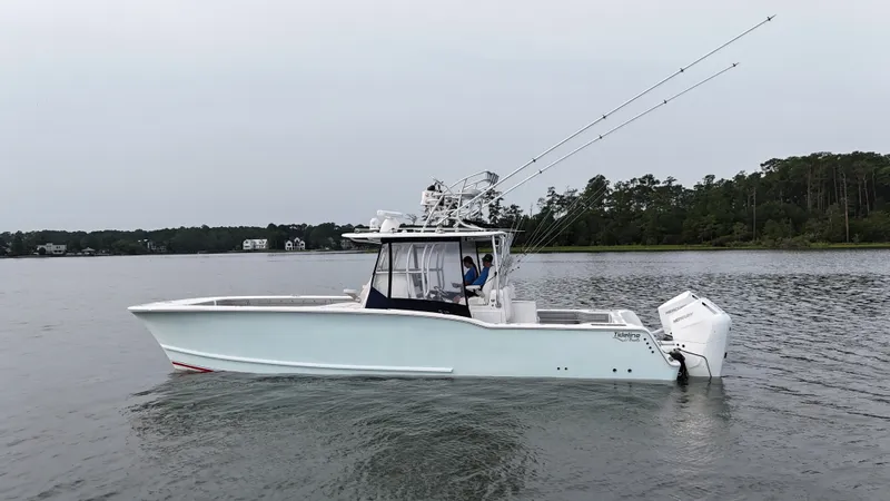 Slide: The Image of A white boat floating on calm water, featuring fishing rods and a covered helm station. - 43