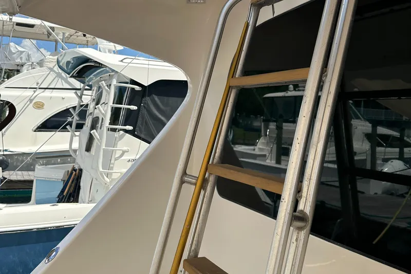 Slide: The Image of 2005 Post 53 Convertible yacht with ladder, docked alongside other boats. - 19