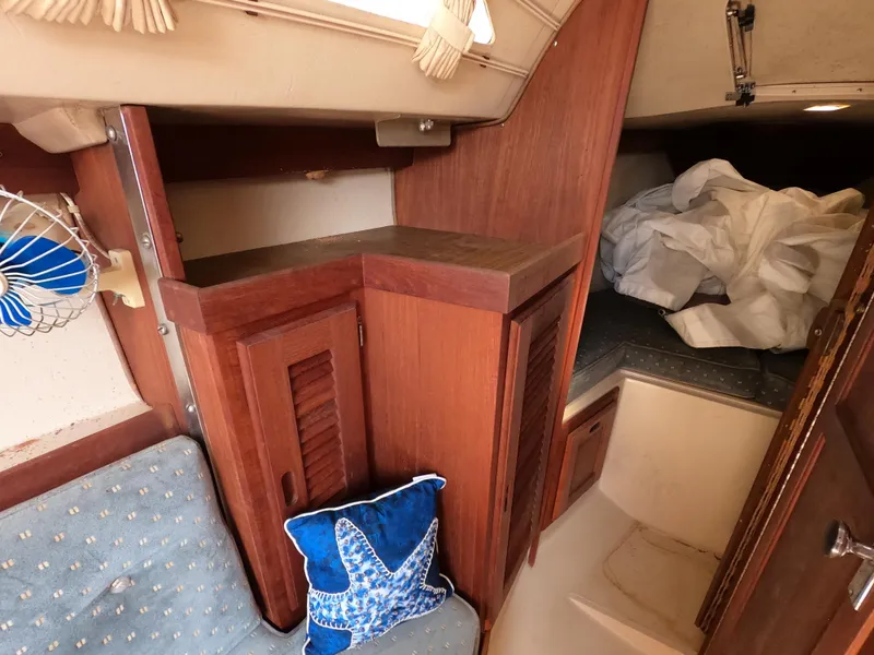 Slide: The Image of Interior of 1985 Catalina 27 sailboat with wooden cabinets and starfish-themed decor. - 12