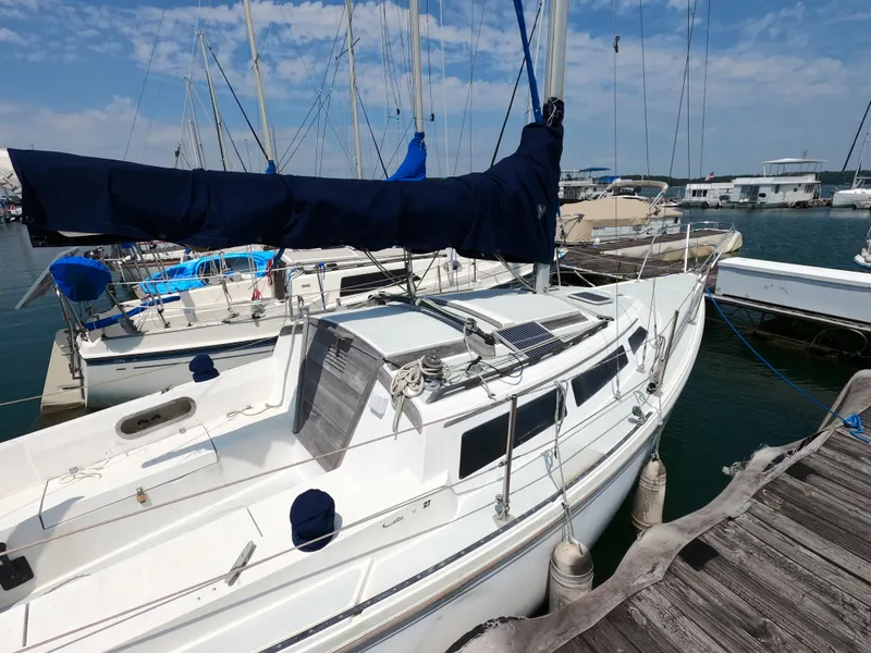 Slide: The Image of 1985 Catalina 27 sailboat docked at marina, featuring white hull and blue sail cover. - 3
