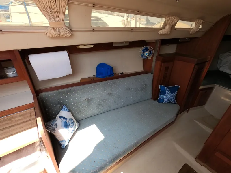 Slide: The Image of Interior of 1985 Catalina 27 sailboat with blue cushioned seating and nautical-themed pillows. - 7