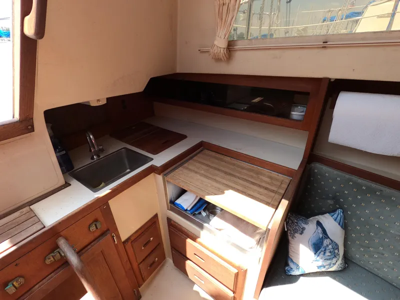 Slide: The Image of Interior of 1985 Catalina 27 sailboat with wooden cabinetry and compact kitchen area. - 8