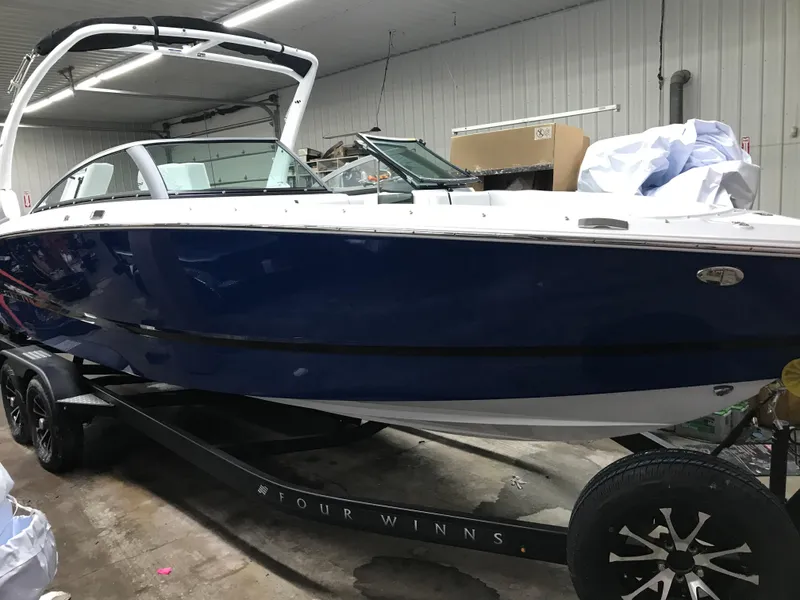 Slide: The Image of 2025 Four Winns H4 boat in a garage, blue hull, on a trailer. - 4