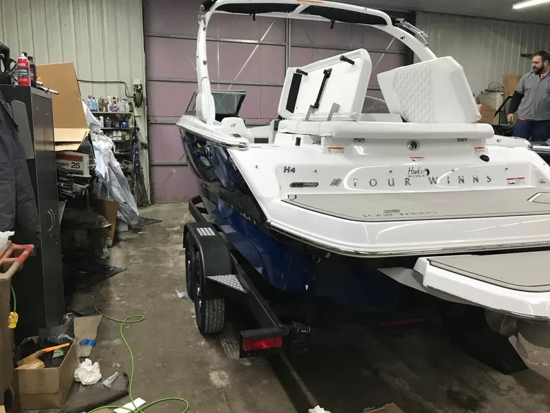 Slide: The Image of 2025 Four Winns H4 boat in a garage, on a trailer, with visible equipment around. - 8